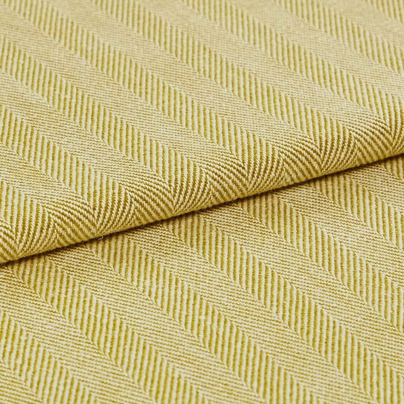 Yellow-green woven fabric with diagonal ribbed herringbone pattern; folded over itself, revealing layered texture; close-up studio-lit view emphasizing the weave and pattern across a flat surface.