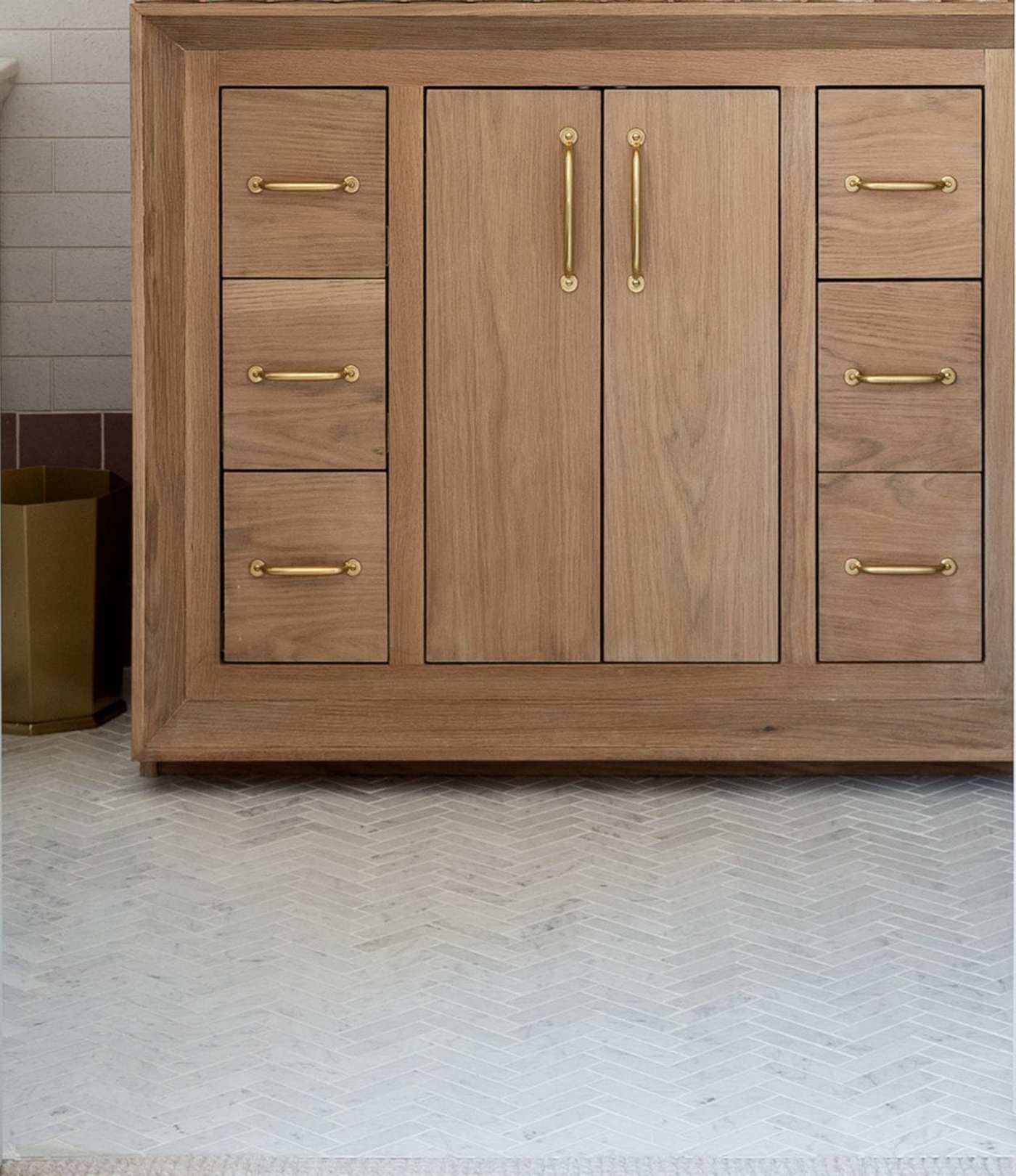 a bathroom with a wooden vanity and brass handles.