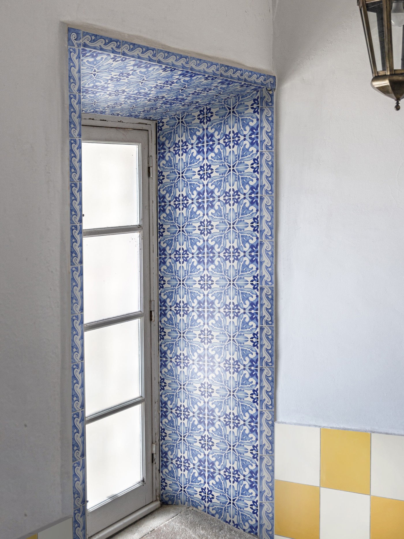 a blue and white tiled wall surrounding a window.