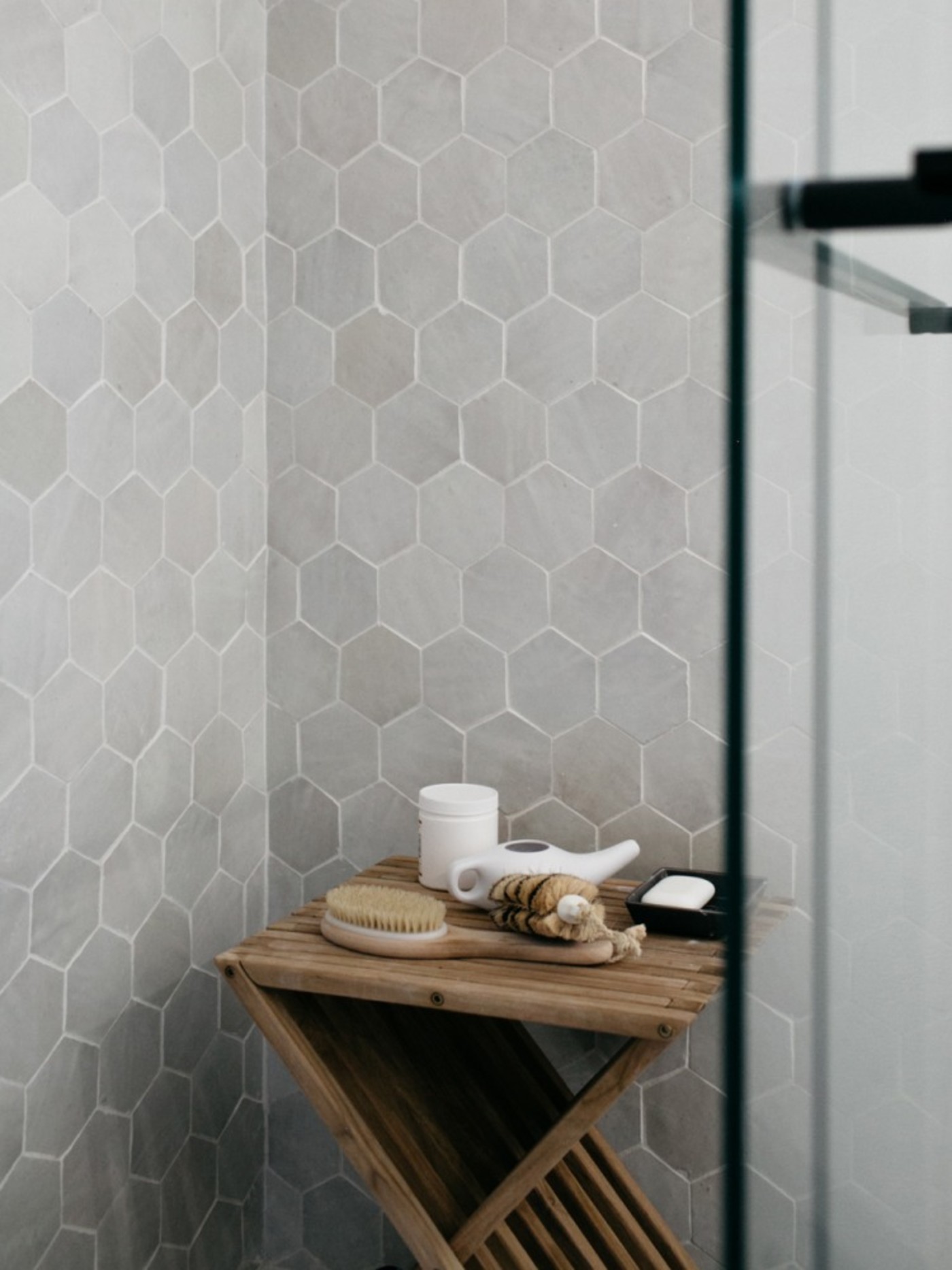 a bathroom with grey hexagon tiles and a wooden table.