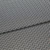 Black-and-white chevron-patterned fabric, folded across the center and showing dense, repeating zigzag lines; lying flat, closely cropped, with even studio lighting highlighting its texture.