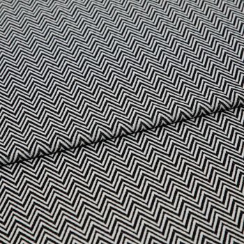 Black-and-white chevron-patterned fabric, folded across the center and showing dense, repeating zigzag lines; lying flat, closely cropped, with even studio lighting highlighting its texture.
