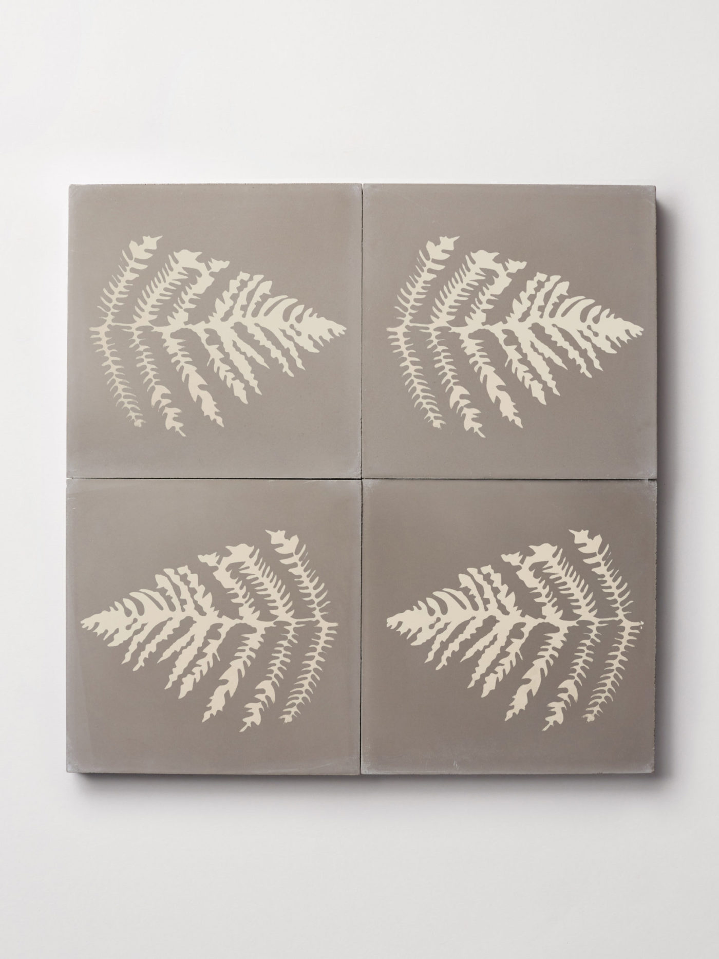 four grey tiles with fern designs on them.