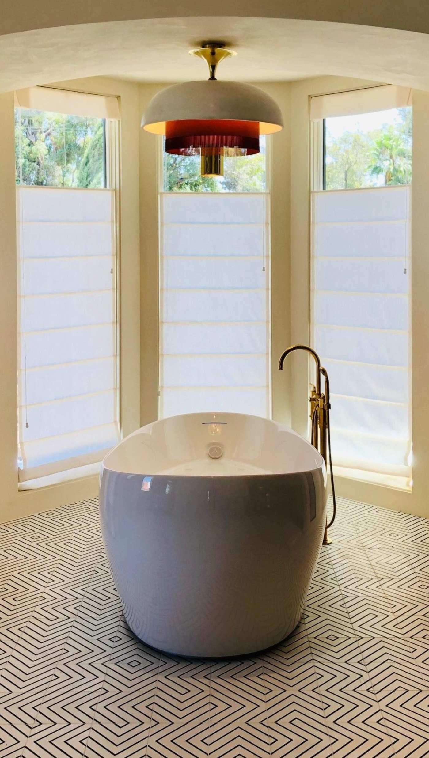 a black and white bathroom with large windows and a tub in the middle.