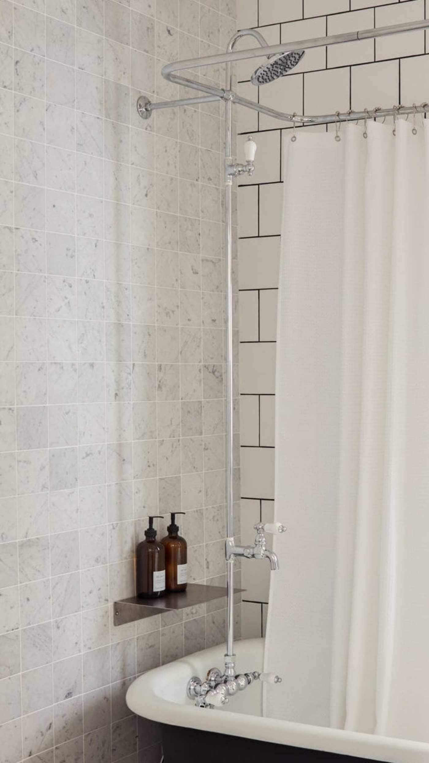 a white tiled bathroom with a black tub and white shower curtain.