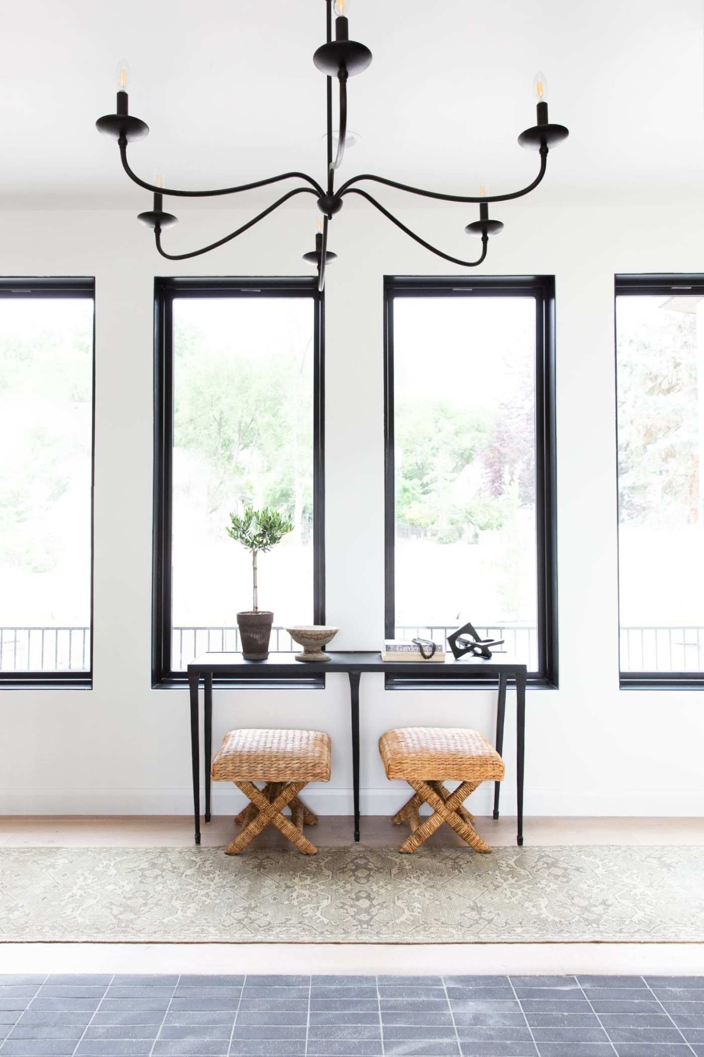 a room with a black chandelier and two stools.