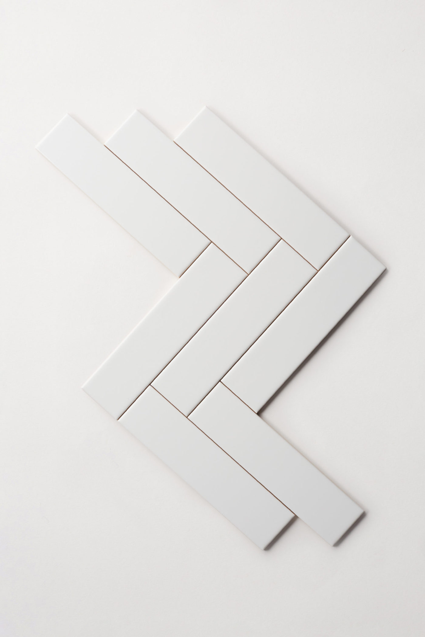 a set of white tiles in a herringbone pattern on a white background.