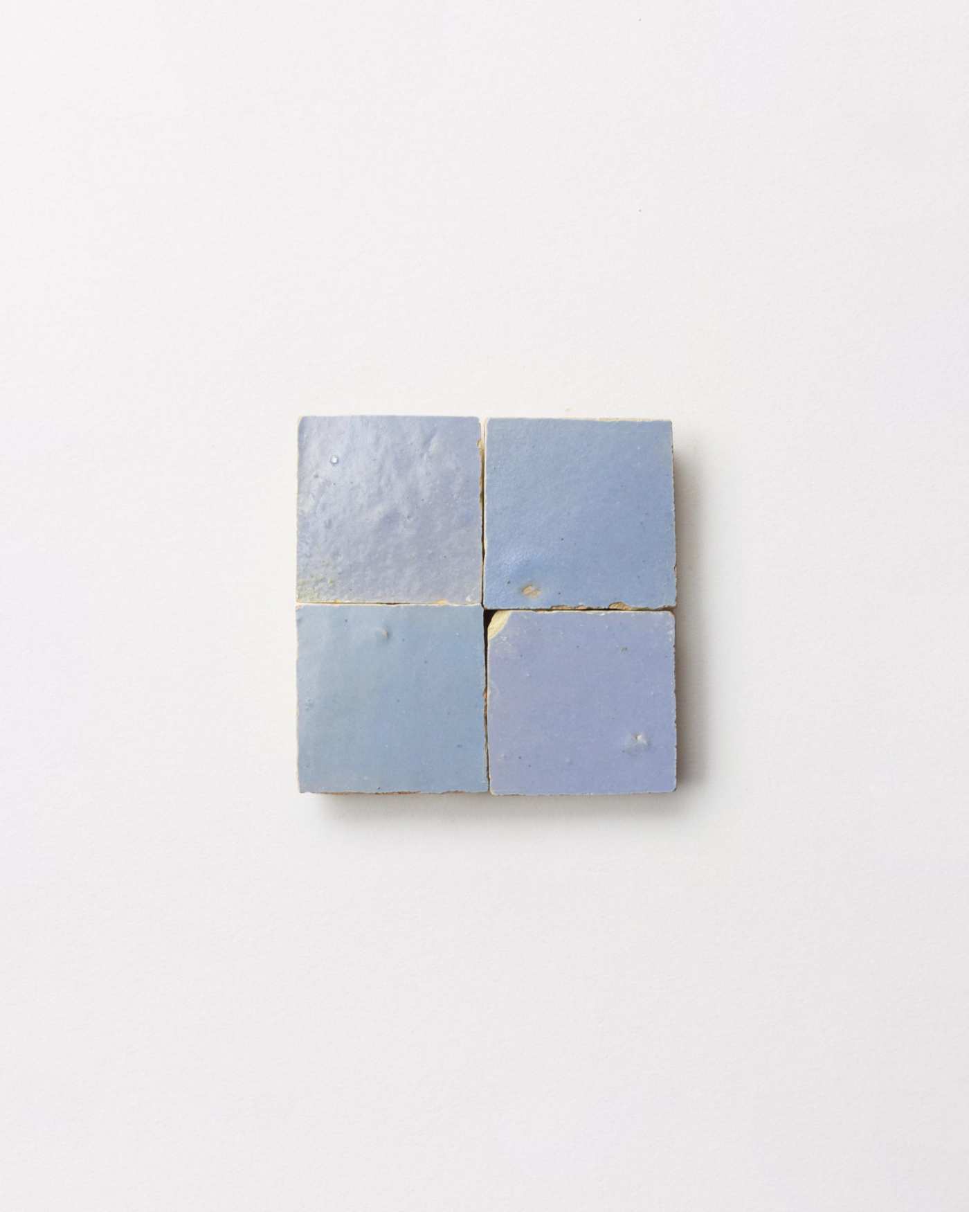 4 squares of blue tile on a white surface.