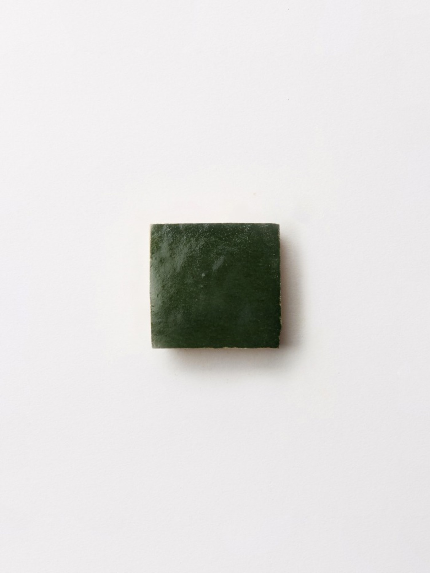 a green square tile on a white surface.