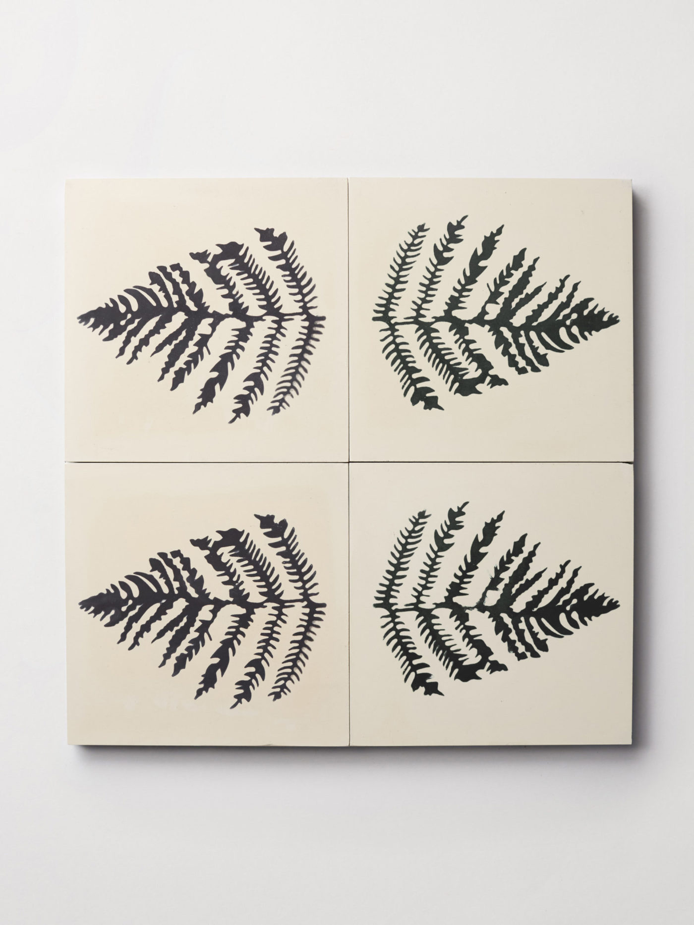 four white tiles with fern leaf prints on them.