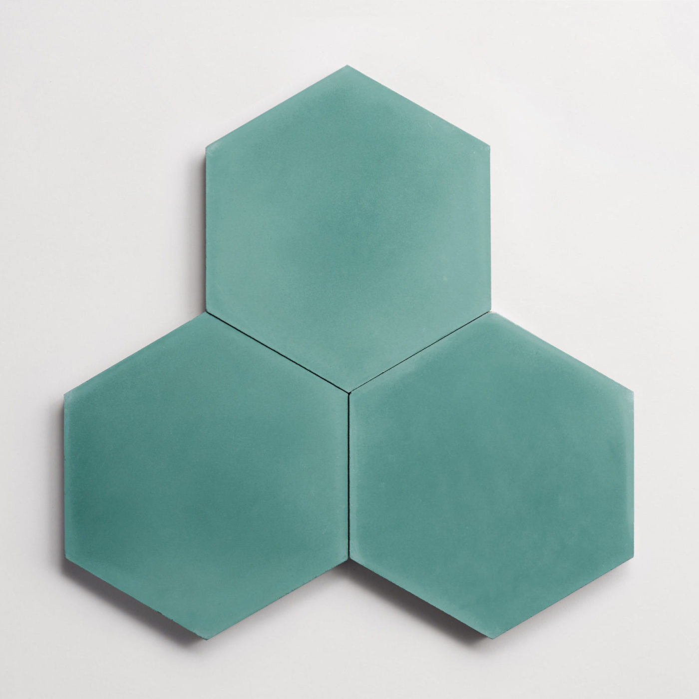 three turquoise-green hexagon tiles on a white surface.