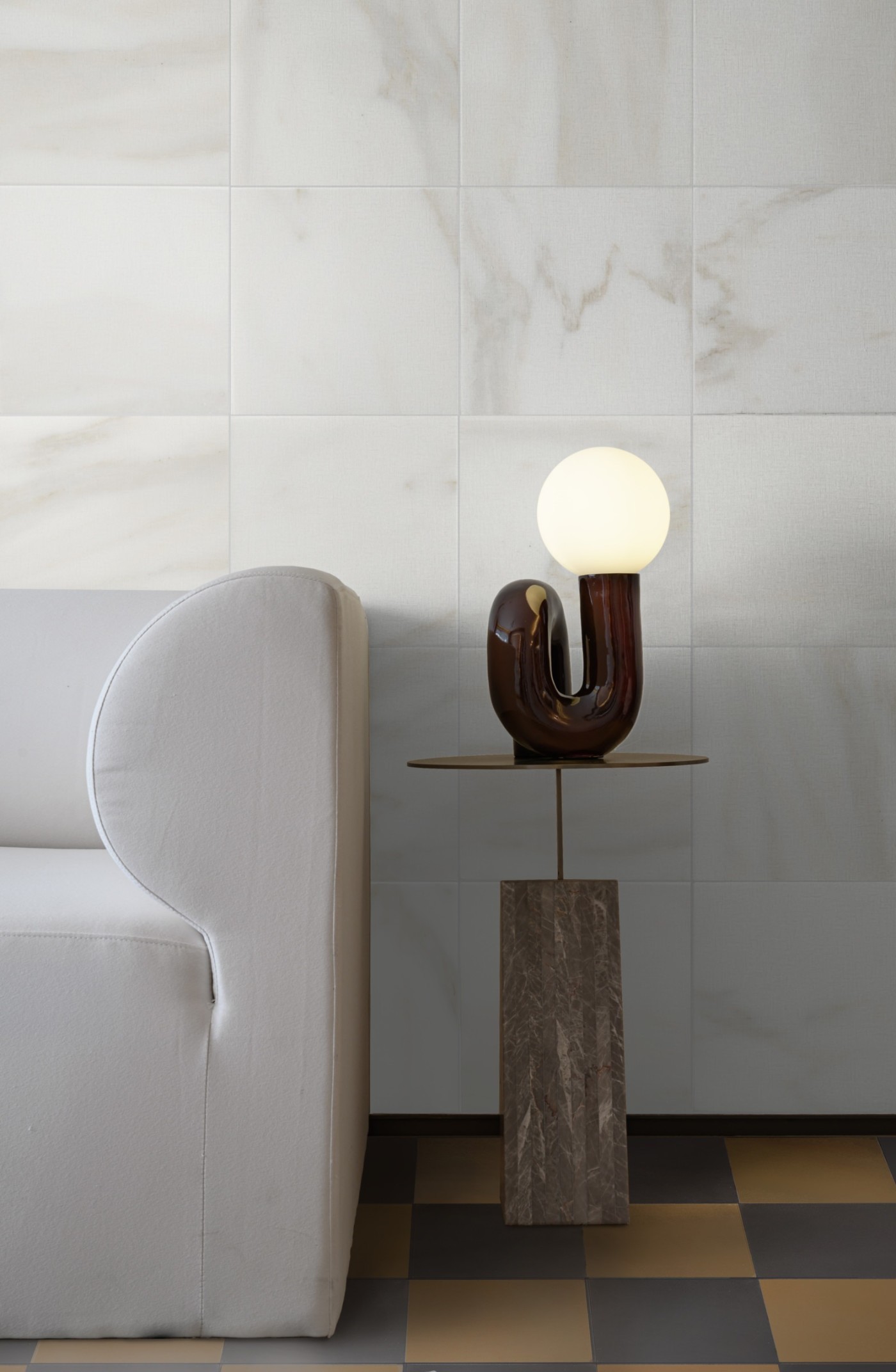 a living room with a white couch and a lamp.