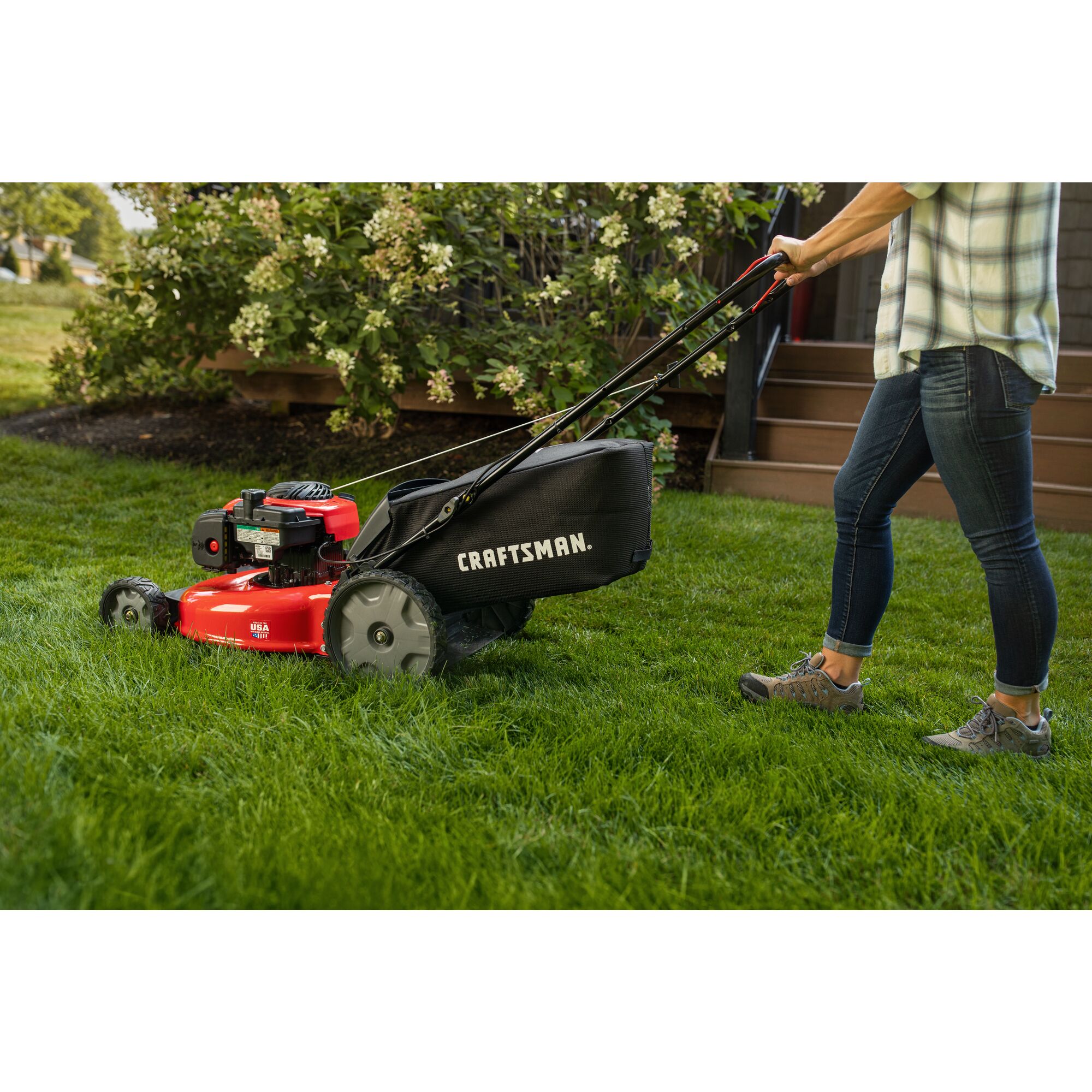 CRAFTSMAN M115 140cc Push Mower in side view mowing the lawn in plaid top and jeans