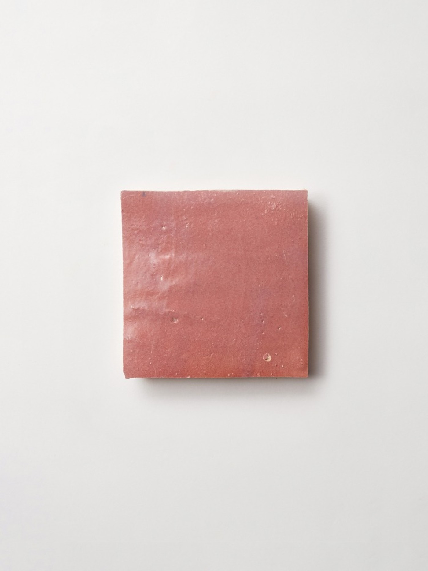 a piece of pink square tile on a white surface.