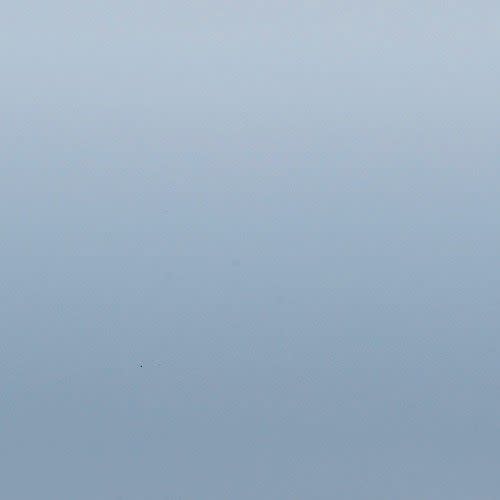 Smooth pale blue gradient surface occupying the frame; shading transitions from lighter at top to slightly darker bottom; evenly lit, featureless field resembling sky or painted wall.