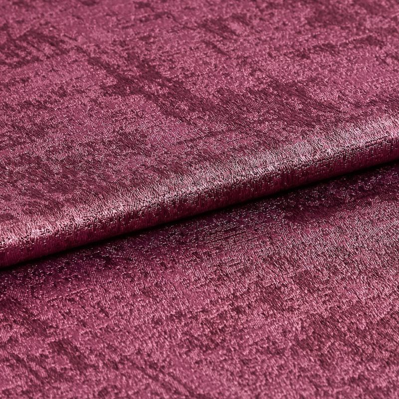 Crushed velvet fabric swatch, folded across the frame with a subtle roll, shimmering and reflecting light; deep magenta color, close-up studio shot emphasizing soft, textured pile.