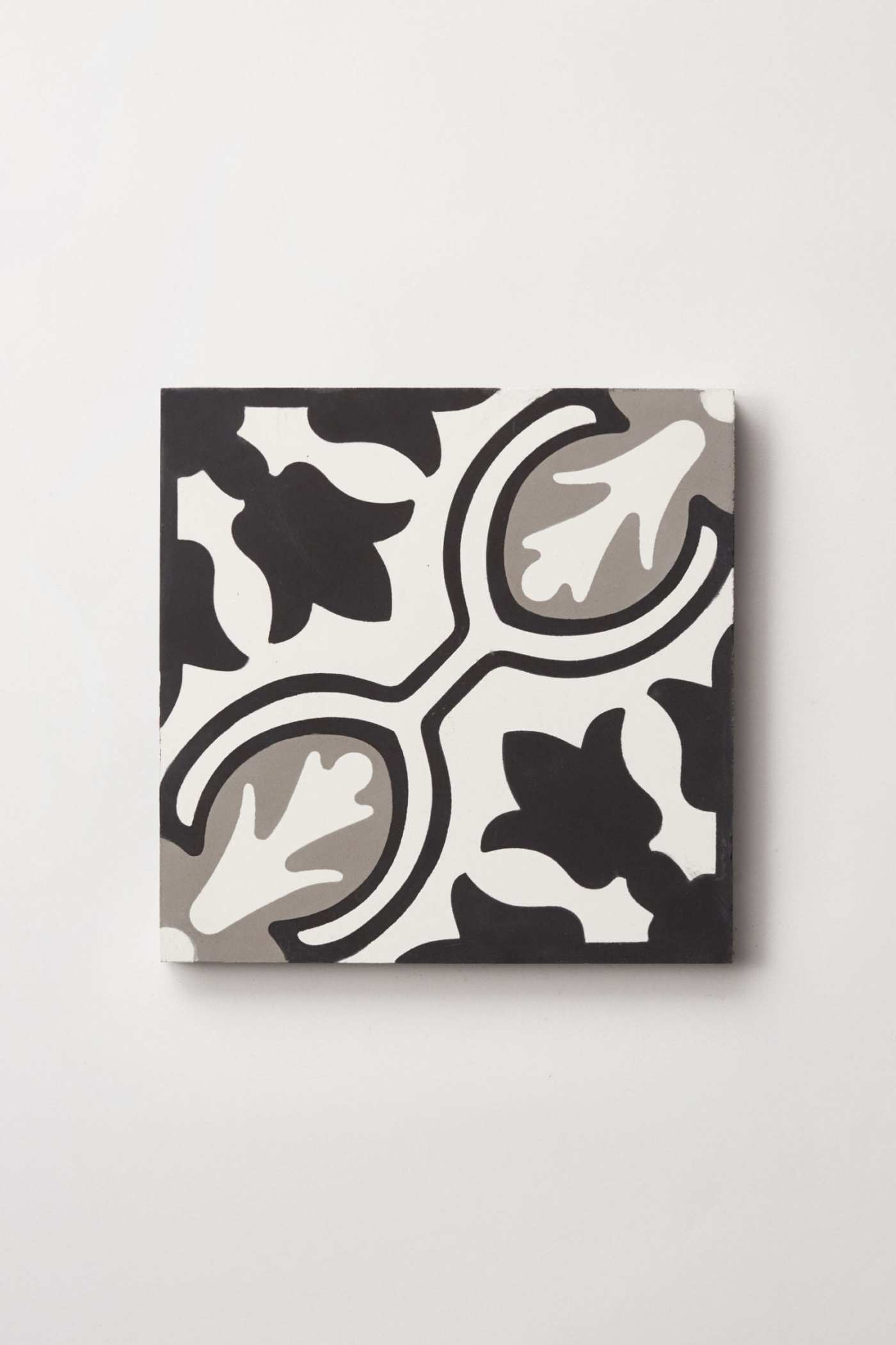 a black and white tile with an abstract design on a white surface.