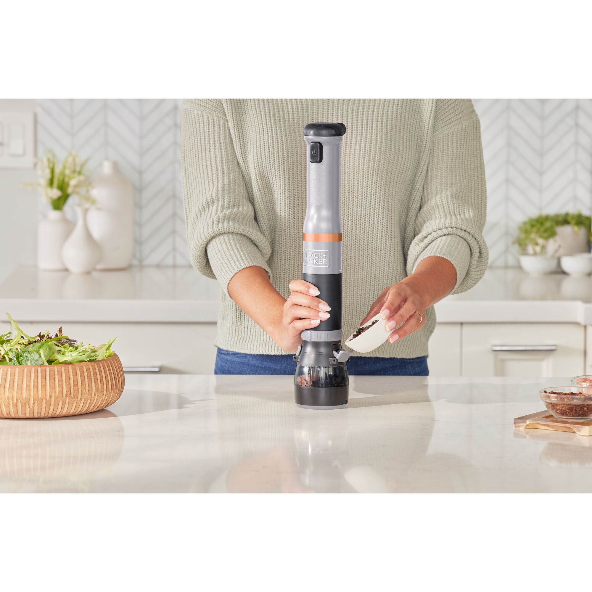 Talent adding peppercorns to the grey BLACK+DECKER kitchen wand spice grinder attachment