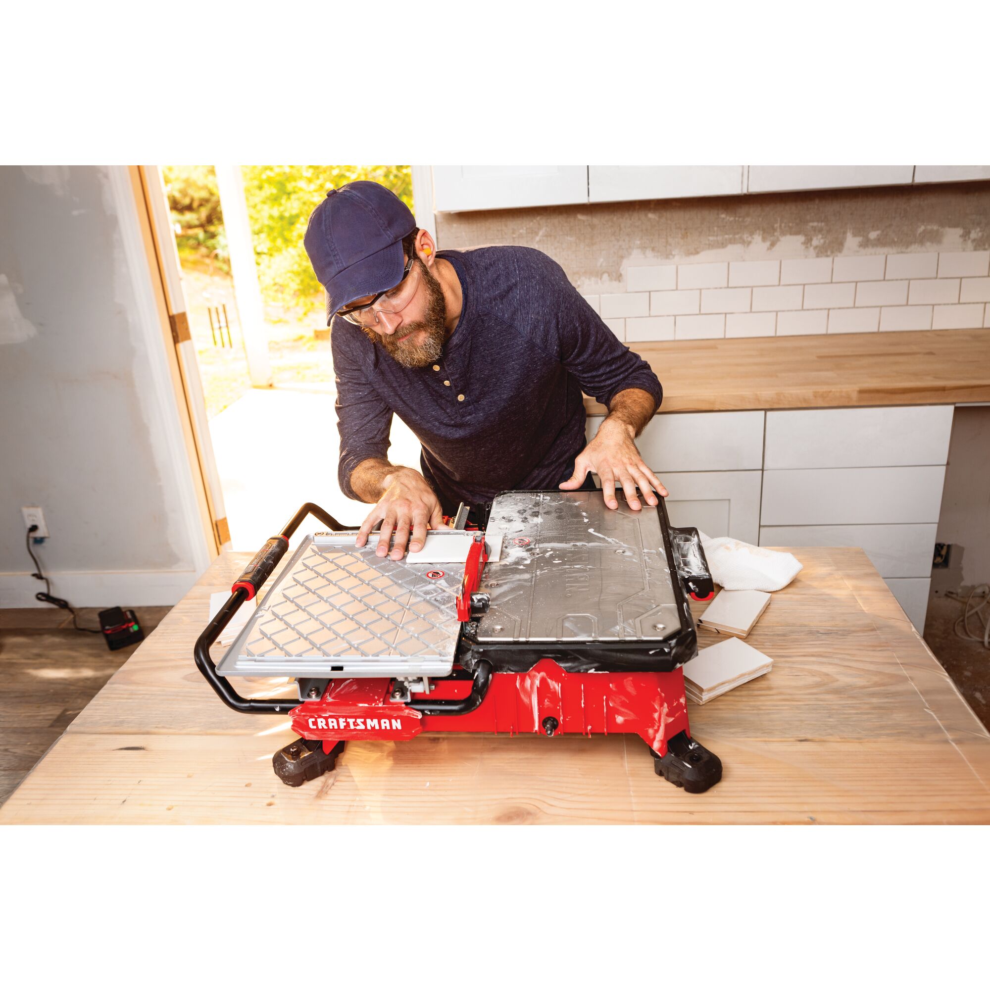 20 volt 7 inch cordless compact wet tile saw being used by a person to cut a tile indoors.