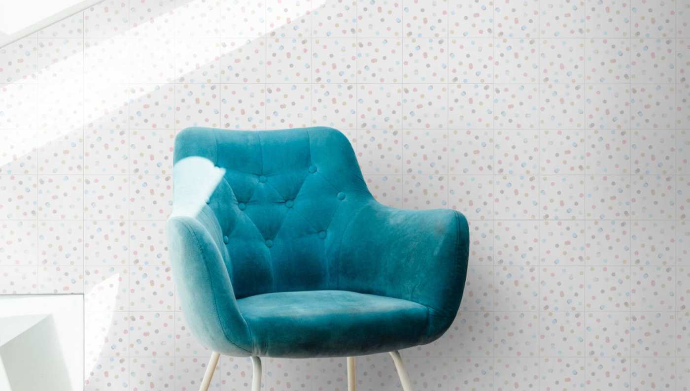 a blue chair in front of a polka dot tiled wall.