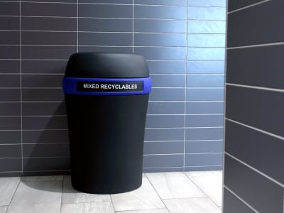 durable black plastic mixed recyclables container with a blue color band and large capacity body at the entrance to a shopping mall washroom area