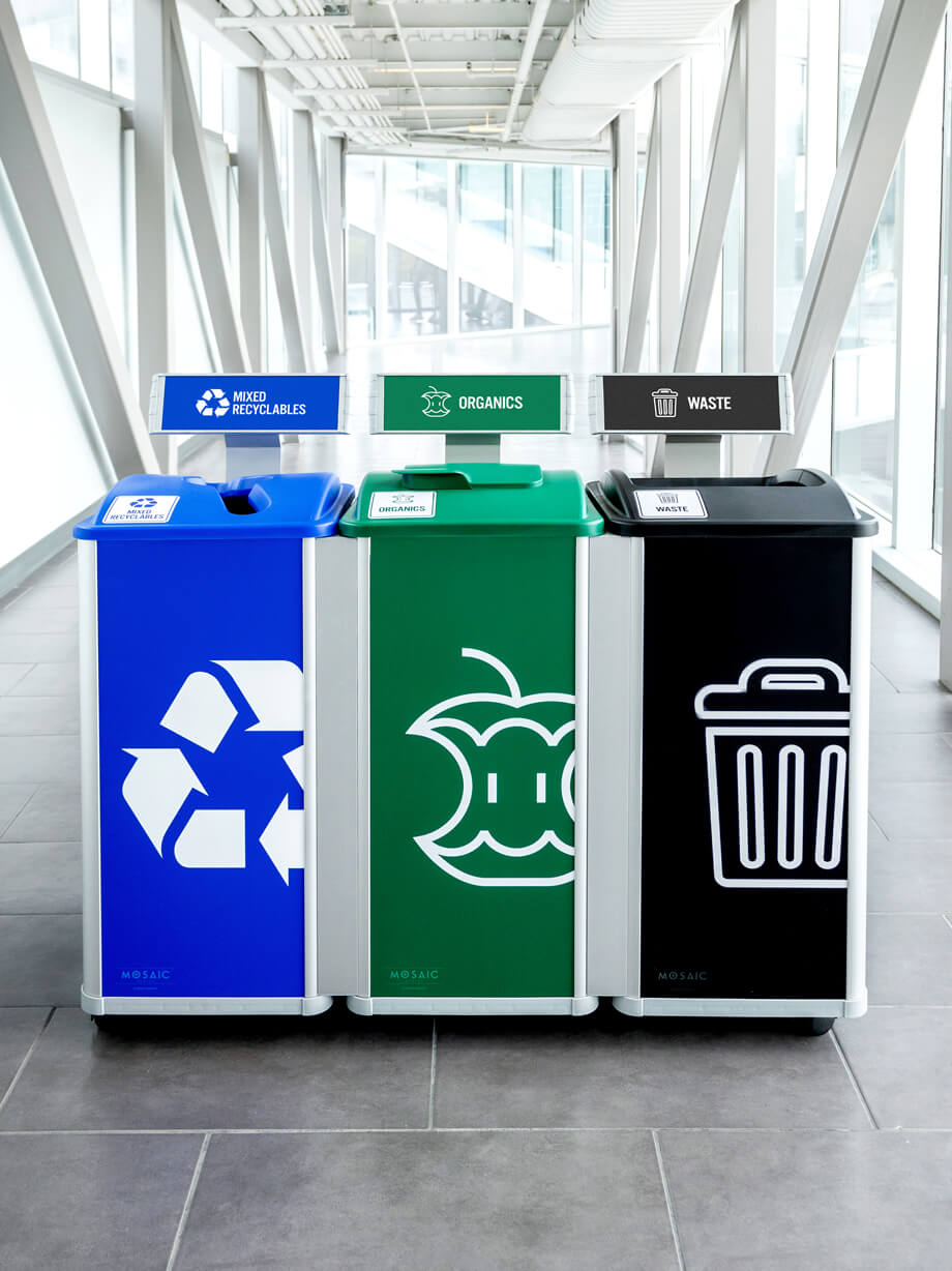 modular triple stream mixed recycling organics and waste station with color coded large body signs and labels with restrictive opening lids in a brightly lit college hallway