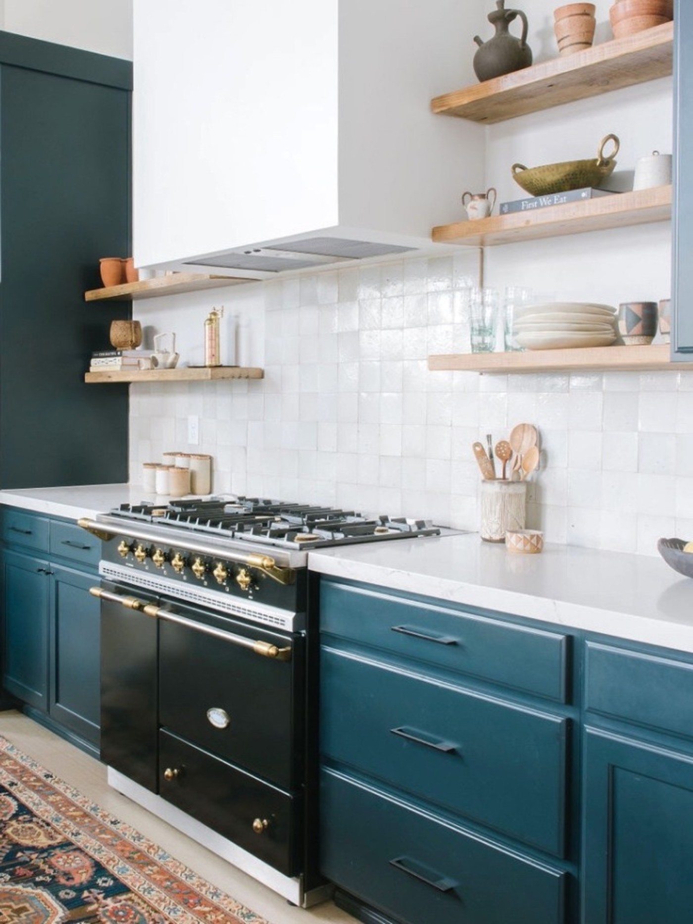 a kitchen with blue cabinets and a rug on the floor.