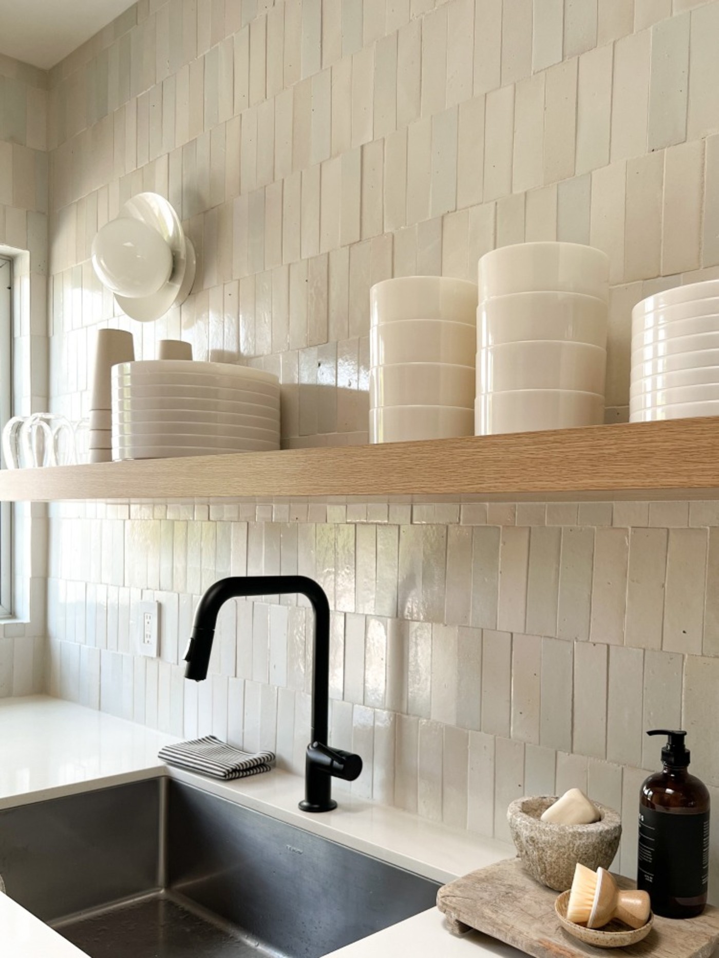 a kitchen with a sink, shelves, and a white tiled backsplash.