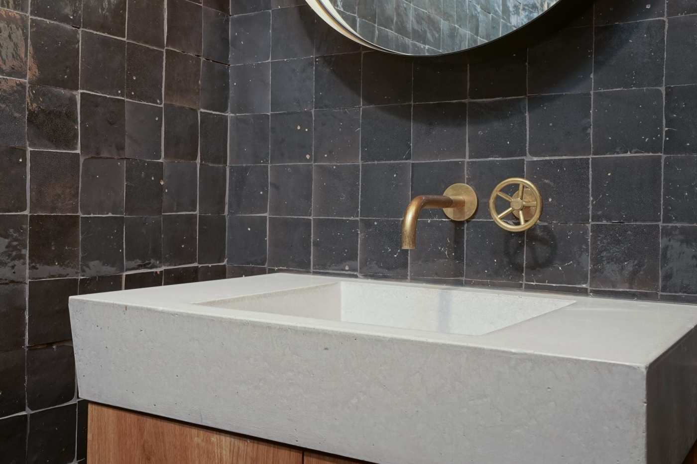 a bathroom with a black tiled wall and sink.