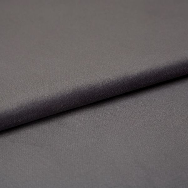 Matte charcoal-gray fabric (object) folded into an overlapping layer, revealing fine soft texture (action); close-up studio shot with even, diffuse lighting and a neutral backdrop (context).