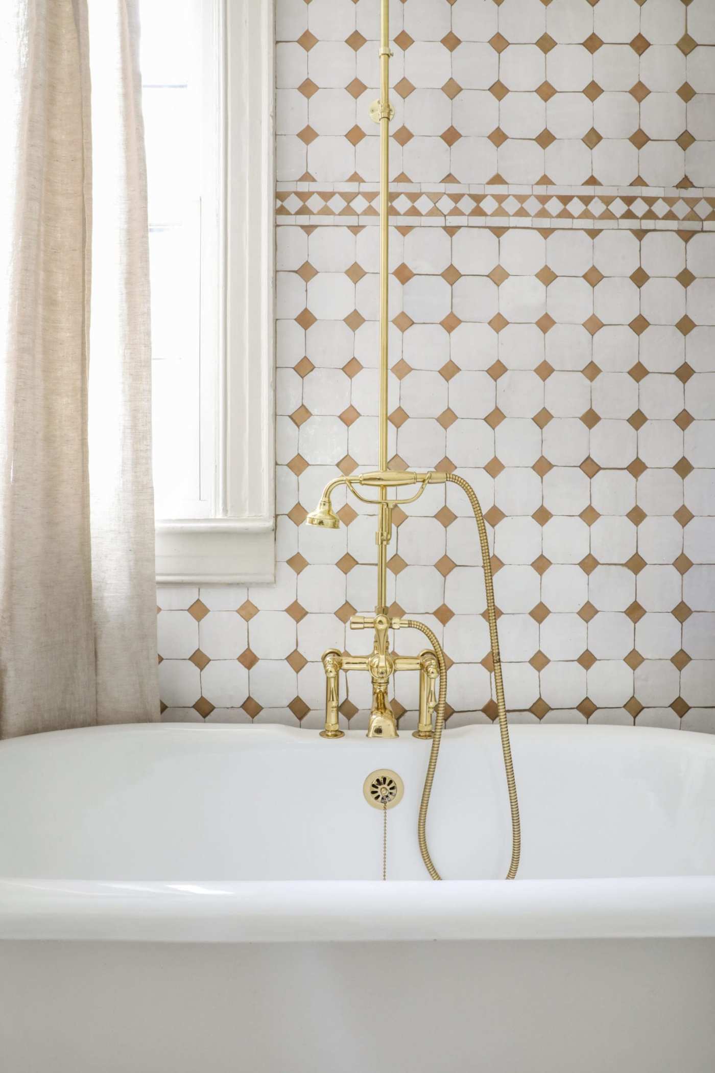 a tiled bathroom wall behind a tub and faucet.