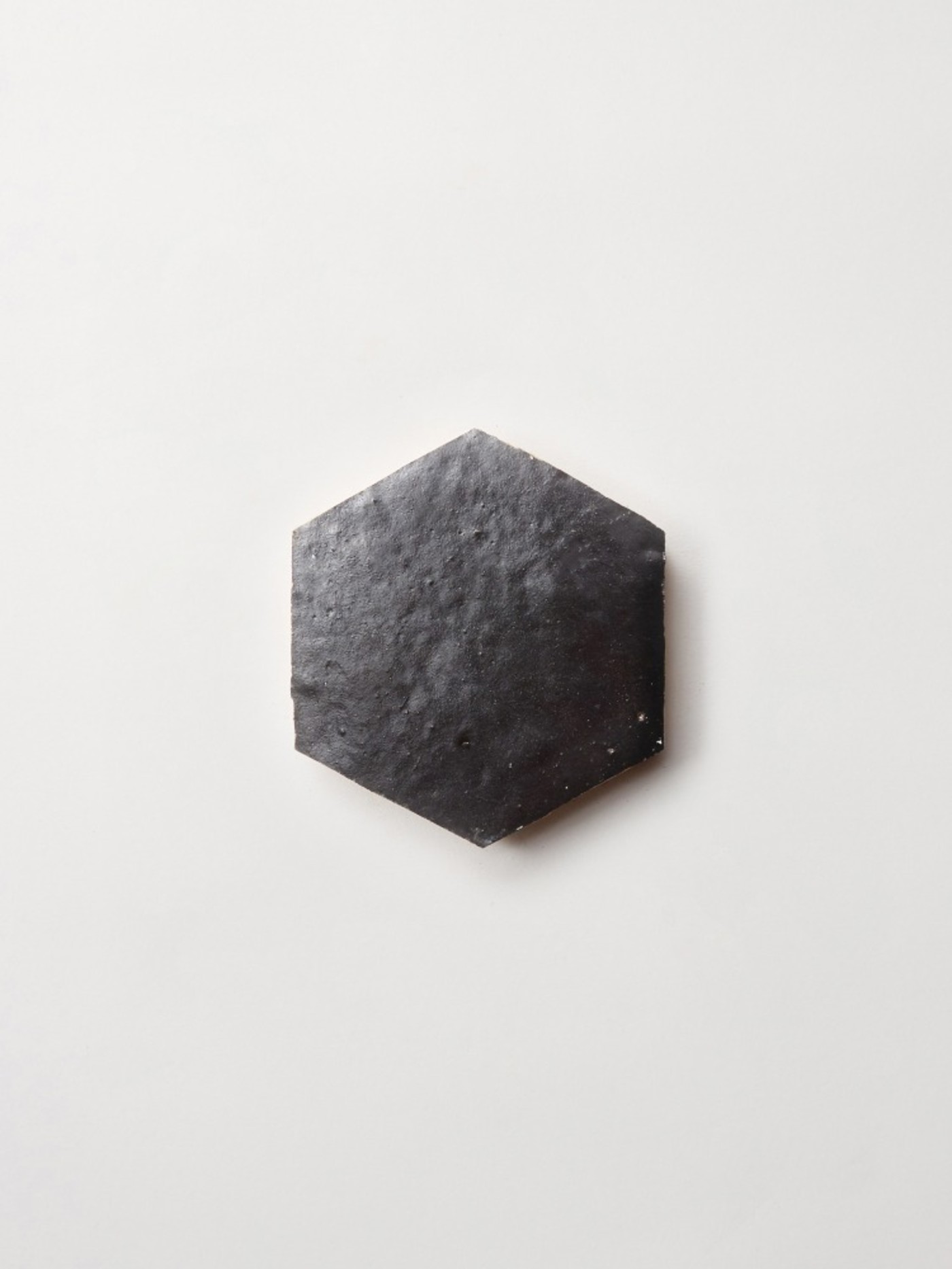 a black hexagonal tile on a white surface.