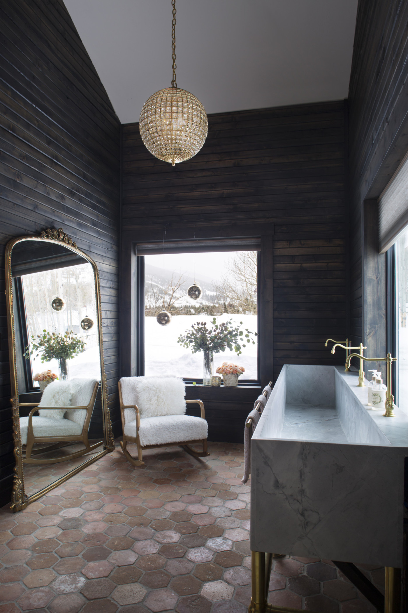 a bathroom with a tiled floor, wood walls and a large mirror.