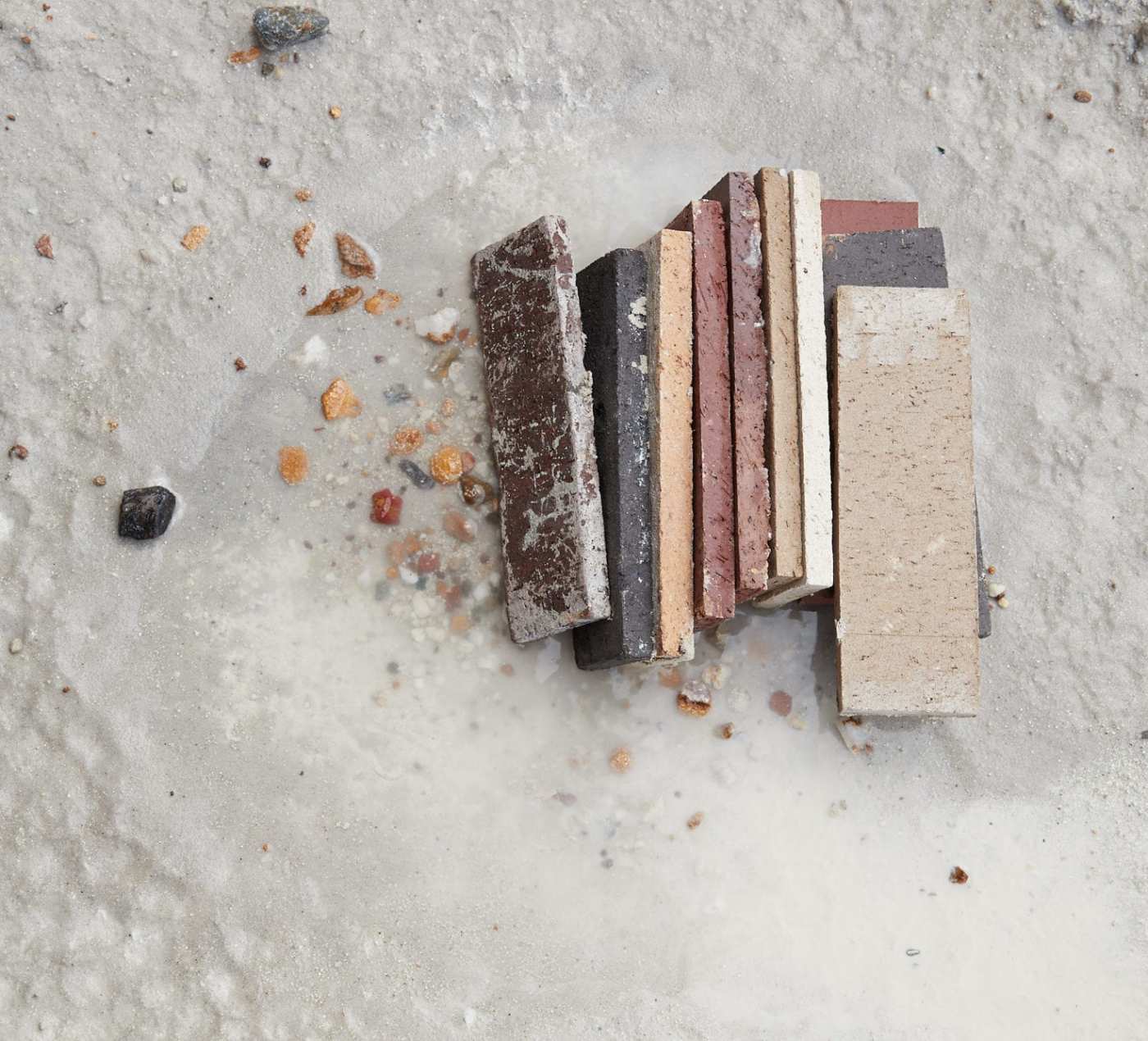 a pile of multicolored brick tiles in the sand.