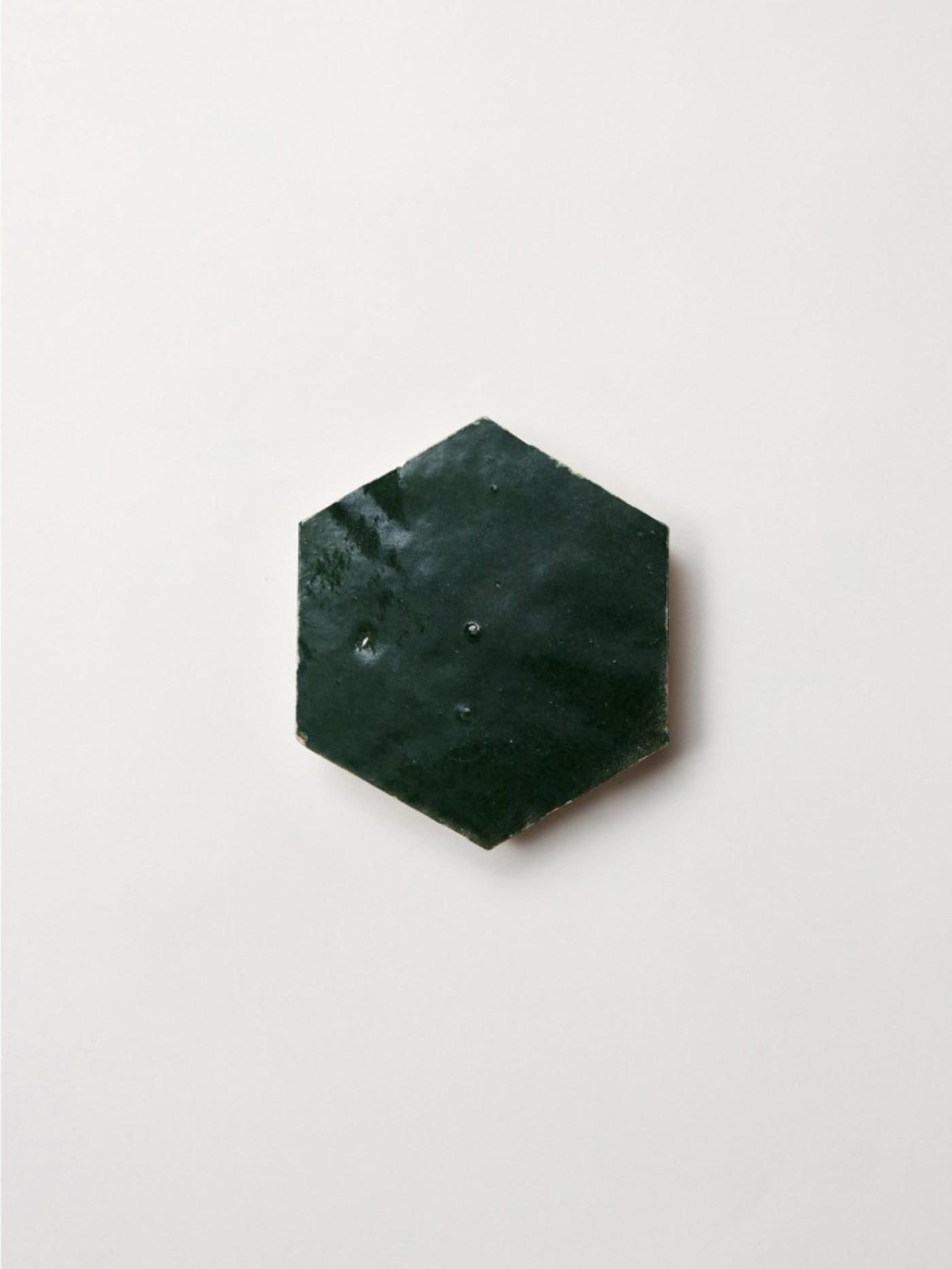 a green hexagonal tile on a white surface.