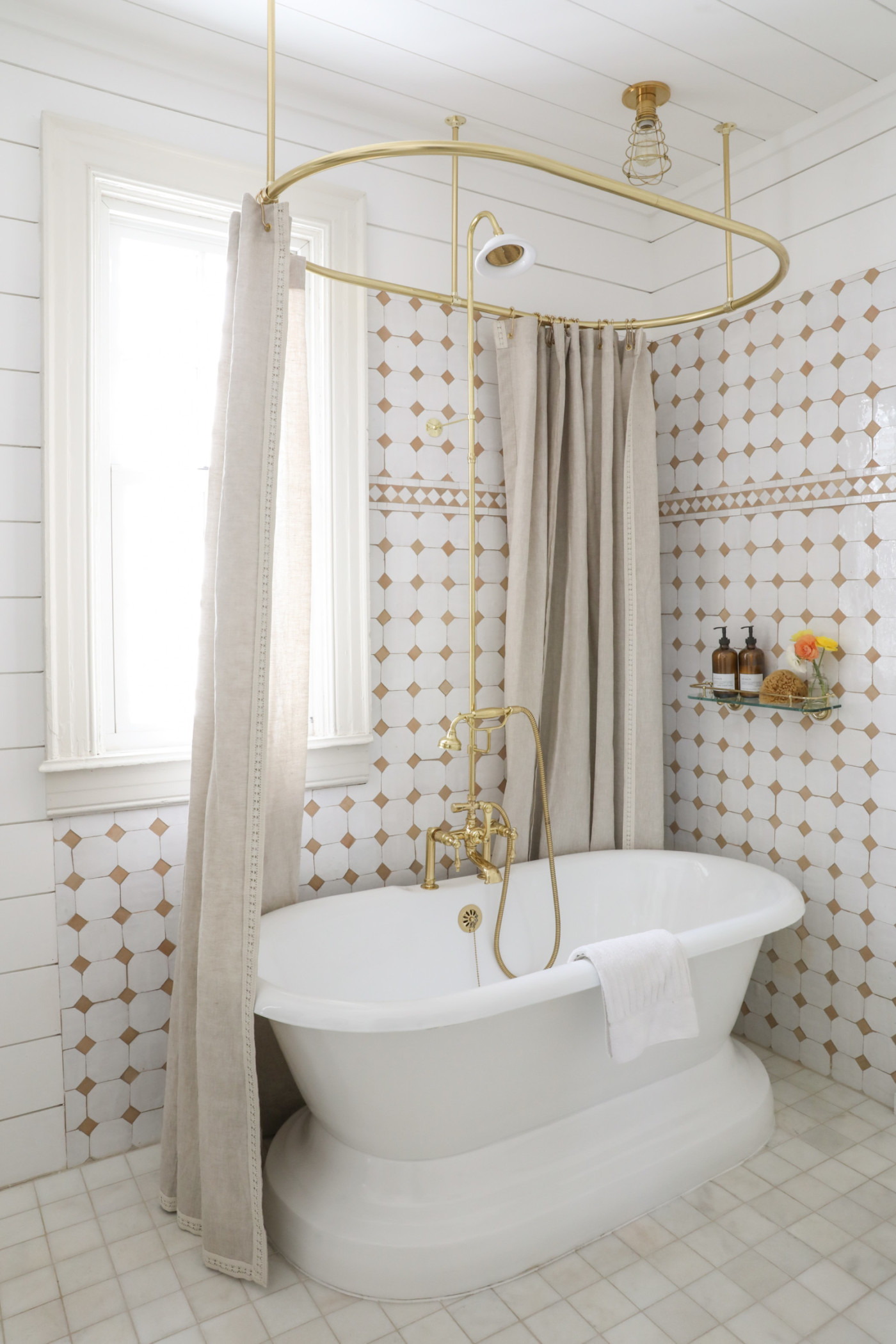 a white and gold bathroom with a tub and shower curtain.