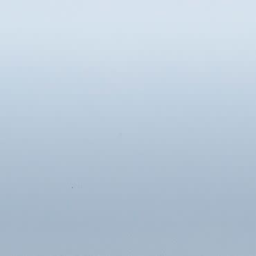 Pale blue-gray gradient surface; uniformly lit and featureless; appears as a smooth wall or sky under soft diffuse lighting with no discernible objects or depth cues.