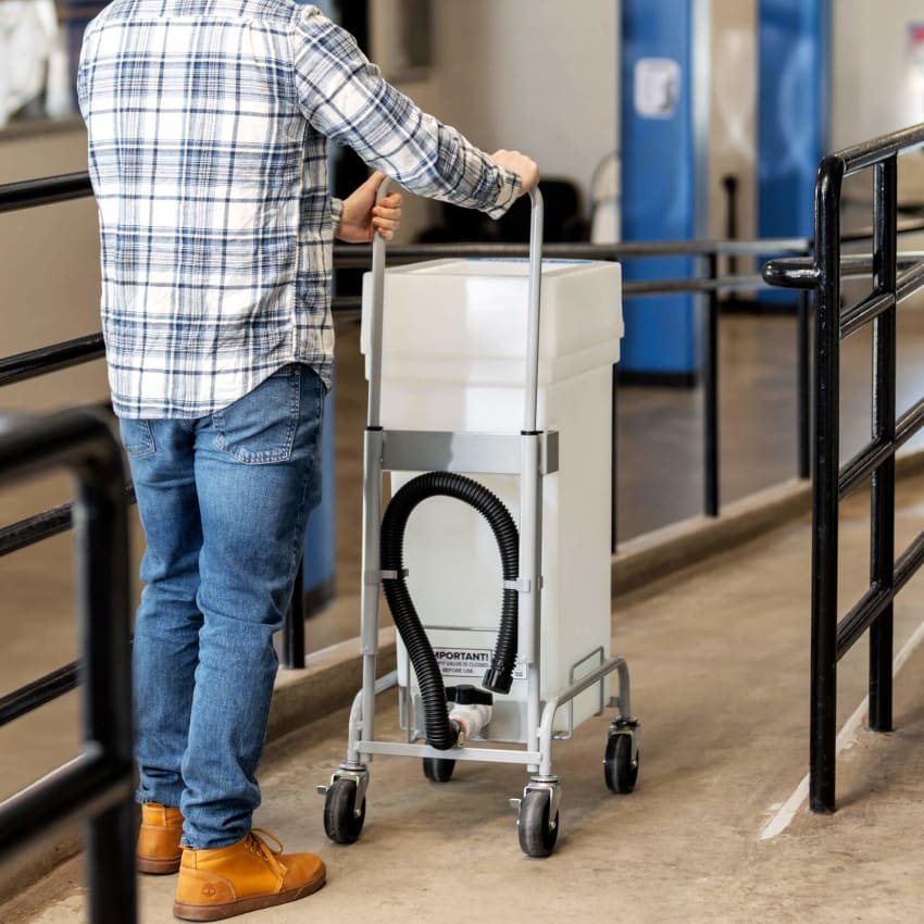 man pushing liquid waste bin to service it in a sports stadium