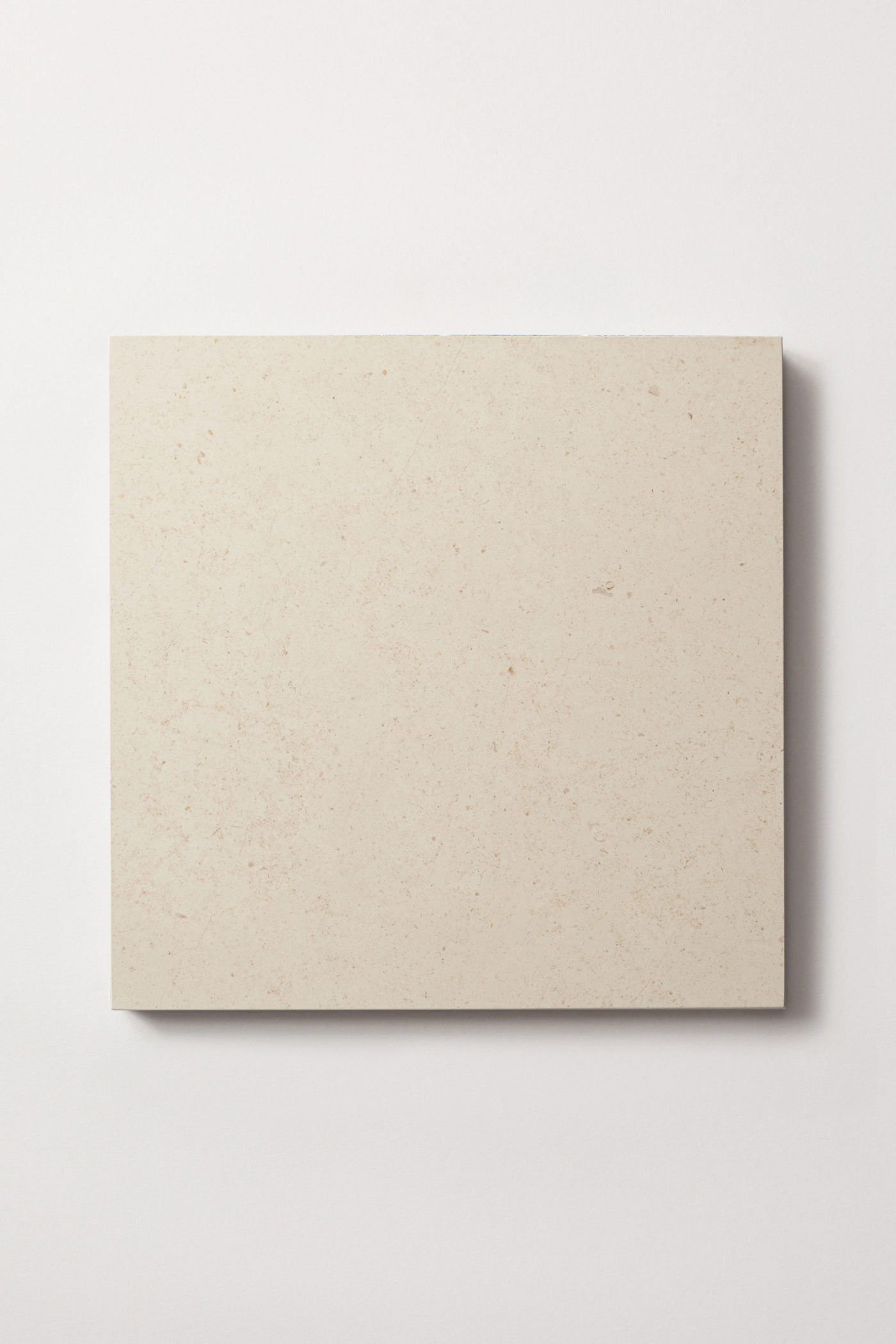 a square white limestone tile on a white surface.