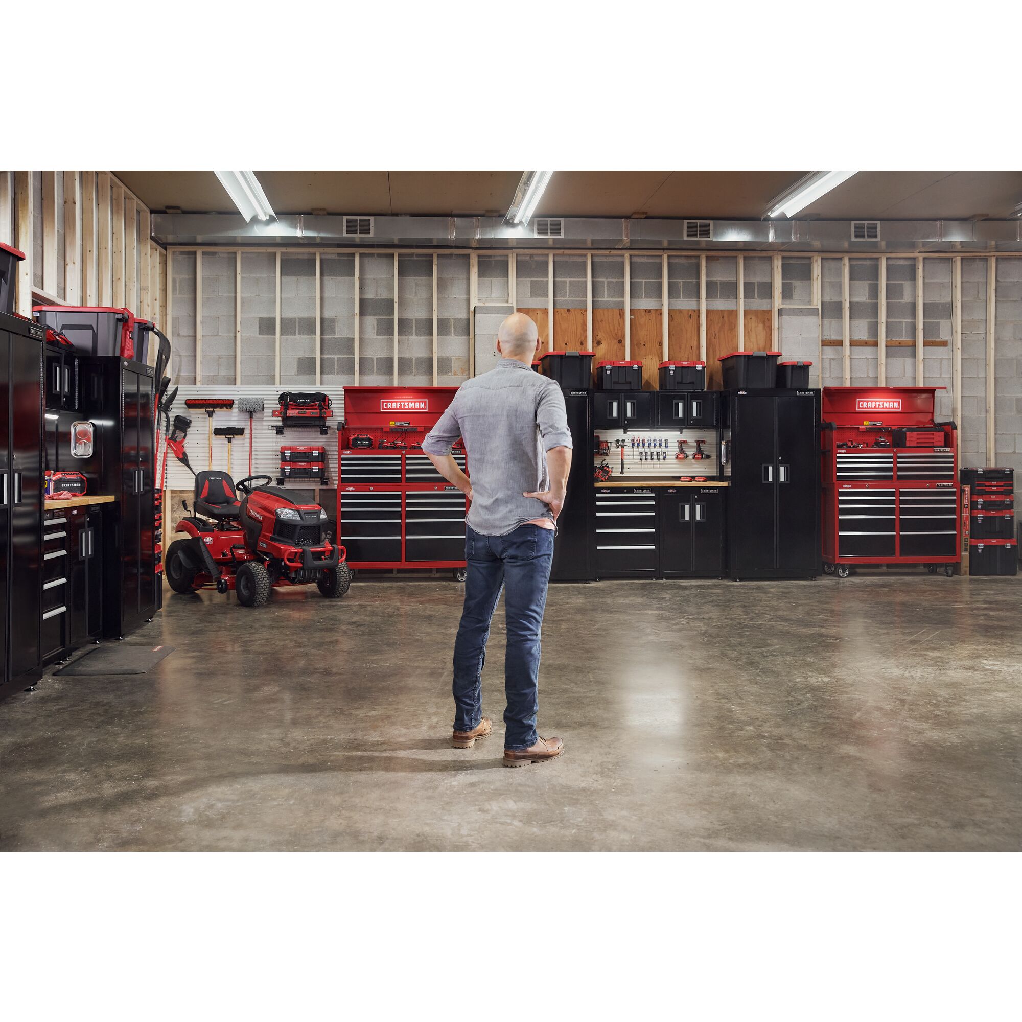 Man handing trimmer on versatrack with garage filled with power tools, storage, outdoor products
