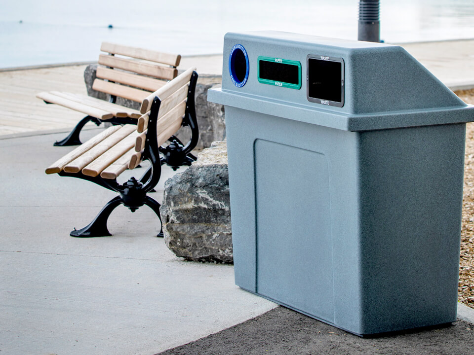 triple stream recycling and trash bin with a heavy duty LDPE plastic body and lid and color-coded restrictive openings outdoors at a local waterfront park