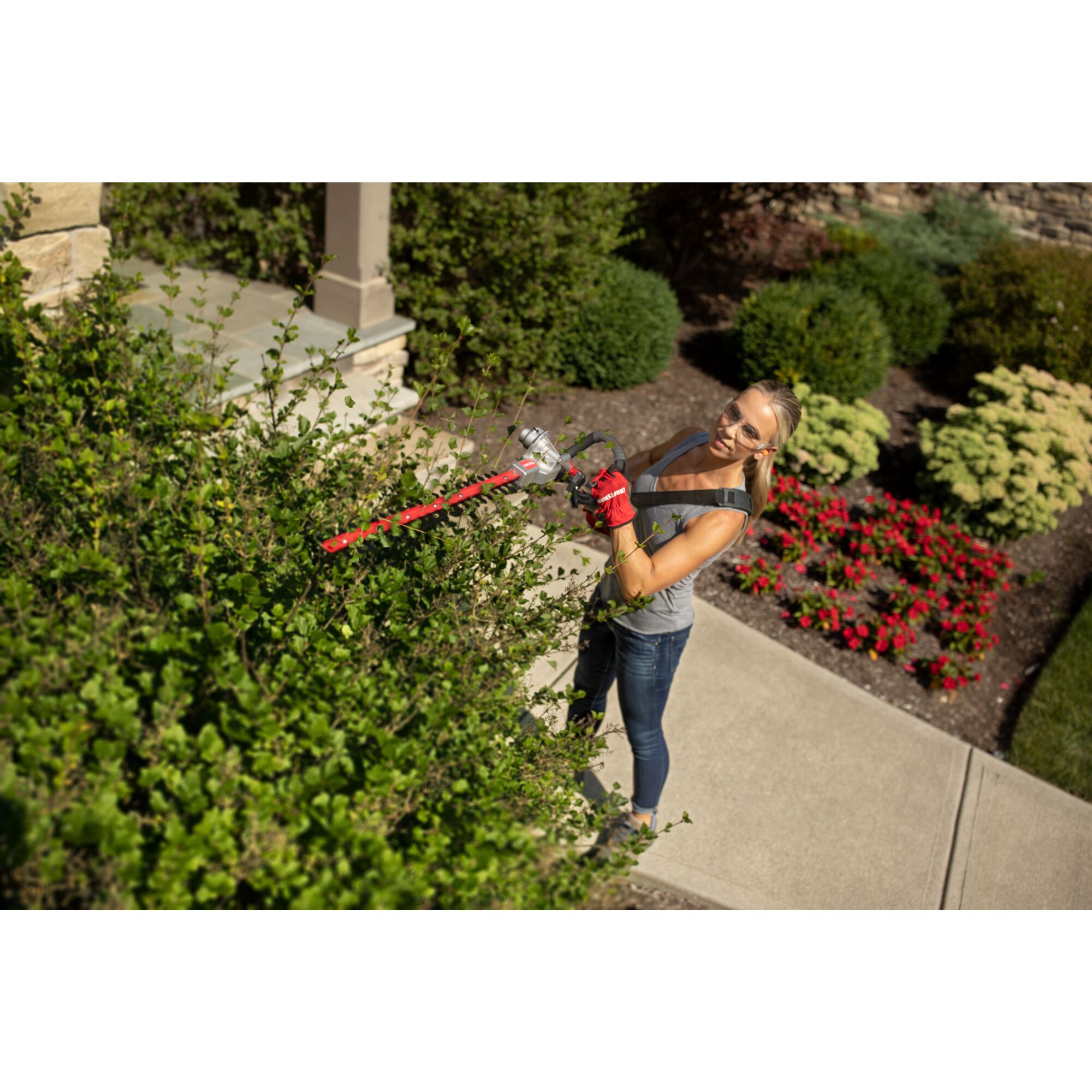 CRAFTSMAN HT2200 Gas Pole Hedge Trimmer trimming top of hedges wearing jeans and gray shirt