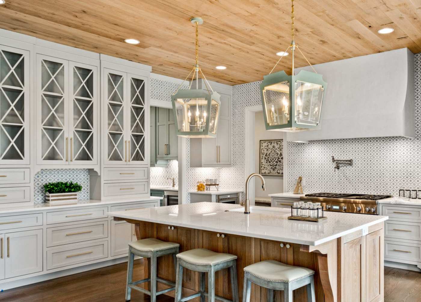 a white kitchen with wooden ceilings and stools.