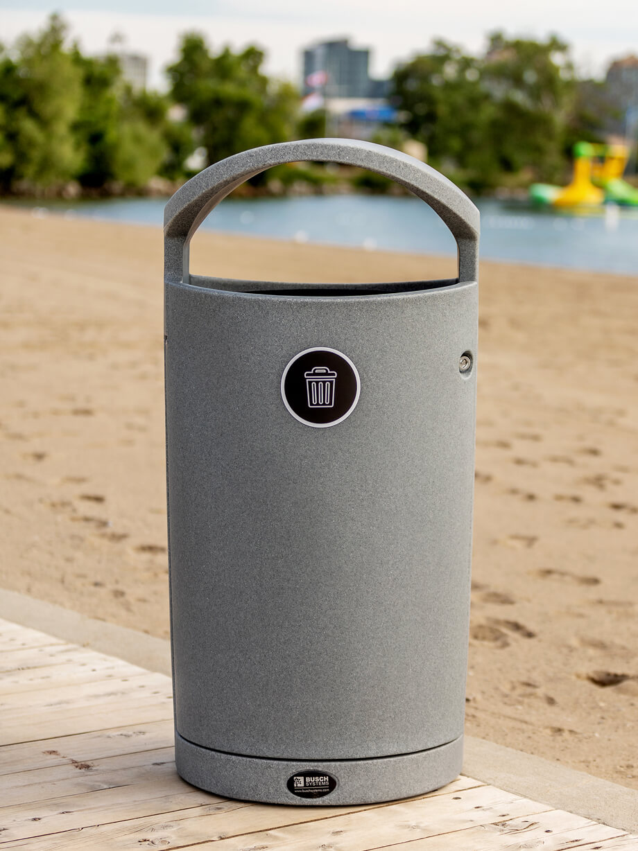 grey plastic waste bin with canopy lid and front load liner with locking door on a boardwalk at the beach
