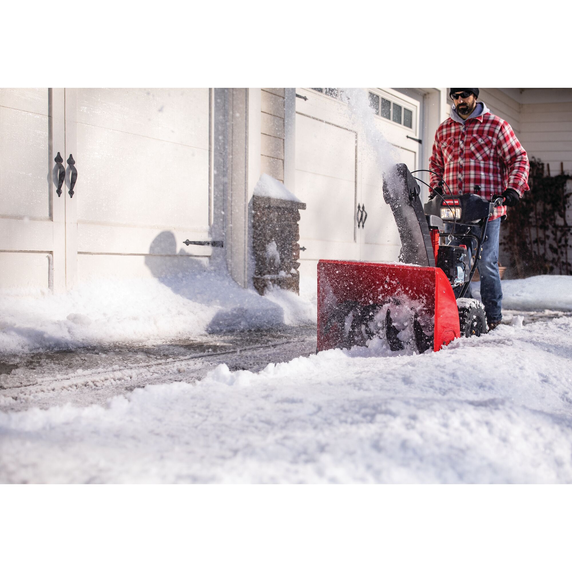 CRAFTSMAN B 28-in 243cc Electric Start Snow Blower clearing snow in the driveway with plaid jacket
