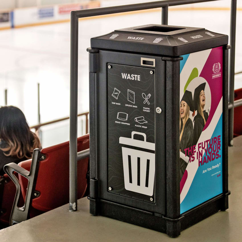 large capacity waste container made from recycled plastics in a hockey arena showing large body signs and advertising space