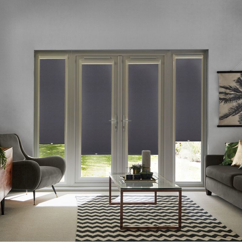 Dark gray roller blinds on four French-door panels and sidelights, lowered to mid-height with small bottom gaps; filtering daylight and blocking view in a living room with sofa, armchair, and glass coffee table.