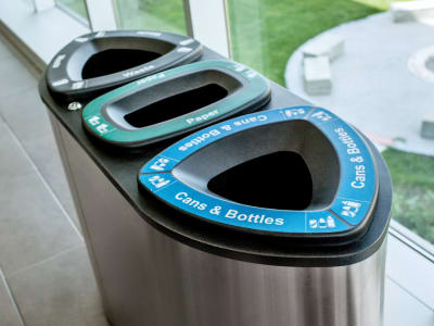 overhead view of a triple waste and recycling container made from stainless steel with a heavy duty steel lid in a college campus