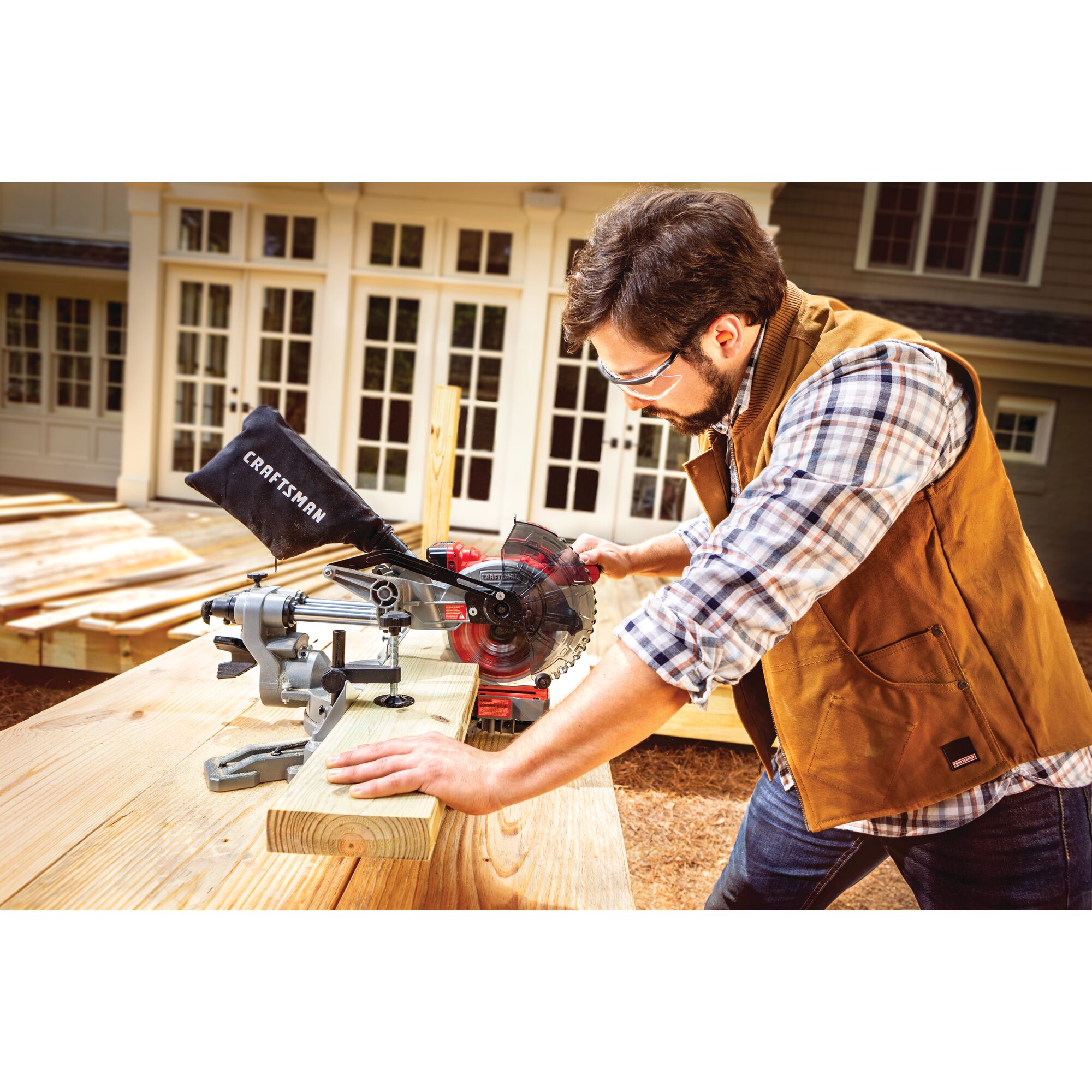20 volt cordless 7 1 quarter inch sliding miter saw kit being used by a person to cut a wooden plank.