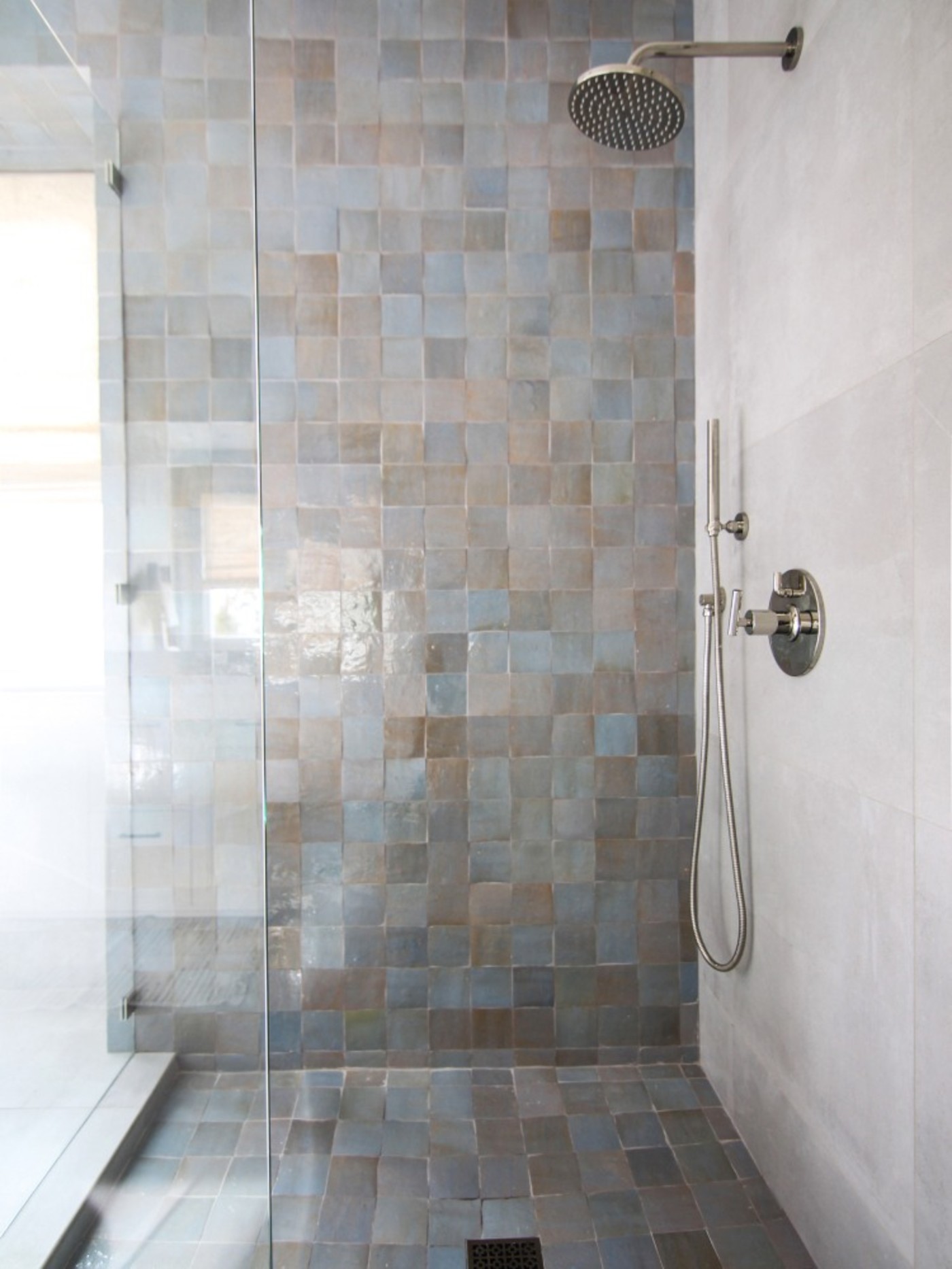 a blue tiled shower with a glass door.